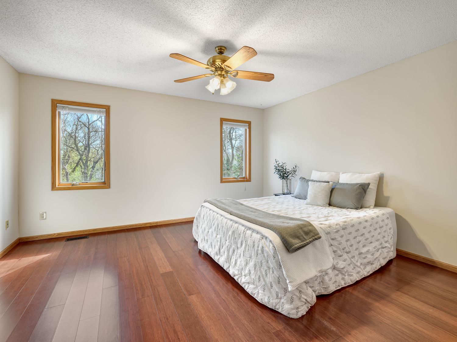 The primary bedroom offers a relaxing retreat with hard surface flooring, abundant natural light, and a ceiling fan for added comfort.