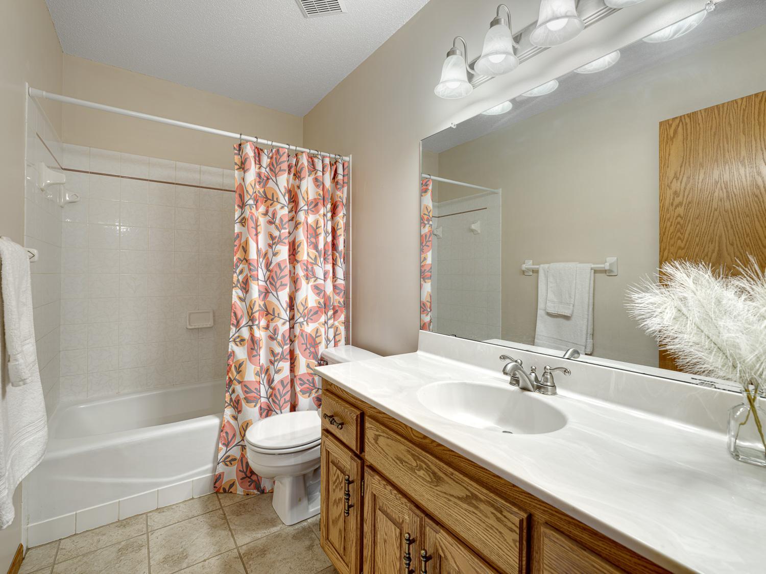This upper level full bathroom is located near both secondary bedrooms. Its spacious layout with an expansive vanity and large mirror makes morning routines easy for everyone.