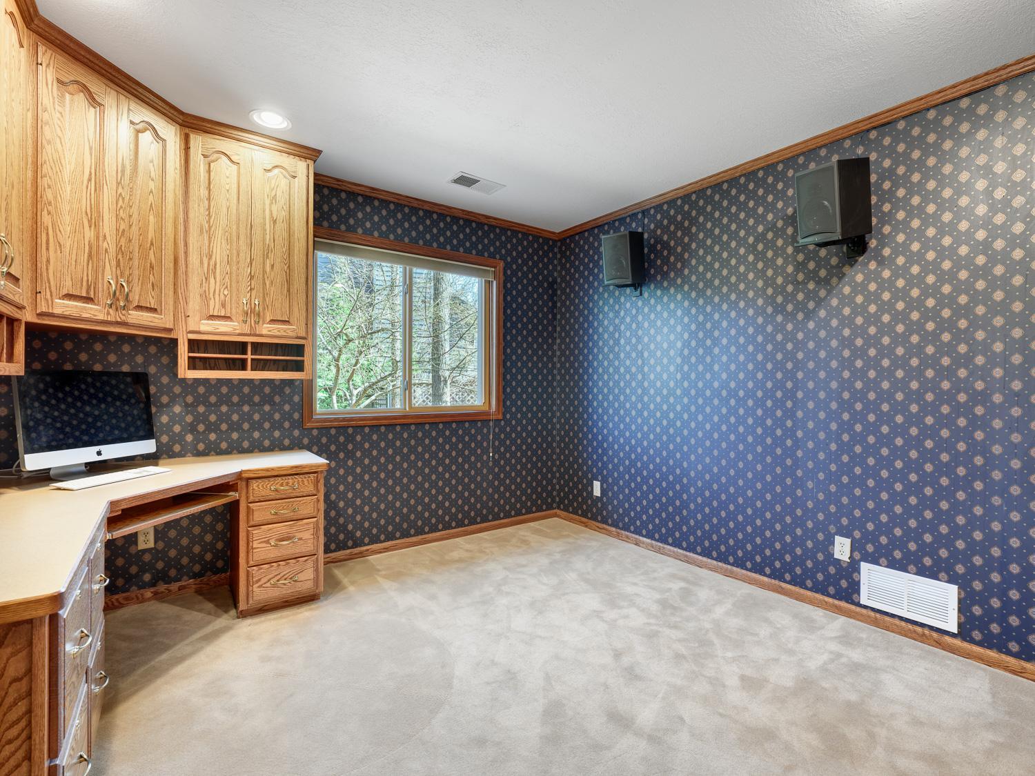 A designated office with a custom built-in desk and shelving delivers a functional and refined workspace.