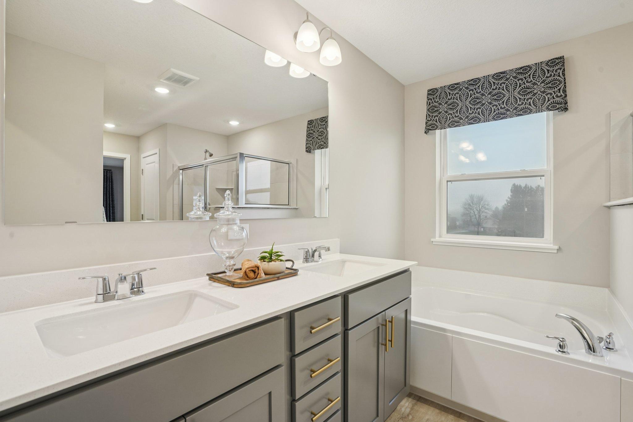 Primary suite offers a large soaking tub and separate shower. Photo of model home, color and options will vary.