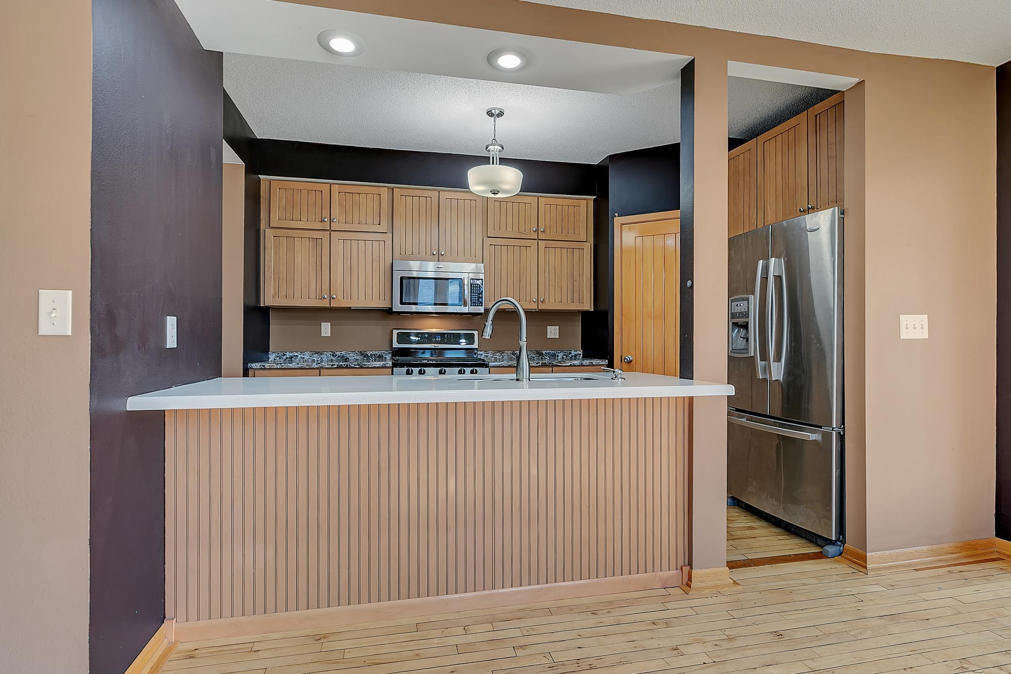 Wonderful kitchen layout with ample cabinets, recessed lighting, breakfast bar and wood flooring.