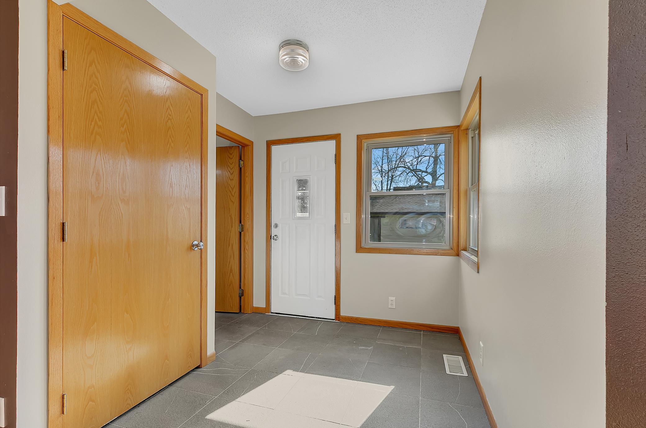 Back entrance door with a closet for outerwear and tiled flooring for easy cleaning.