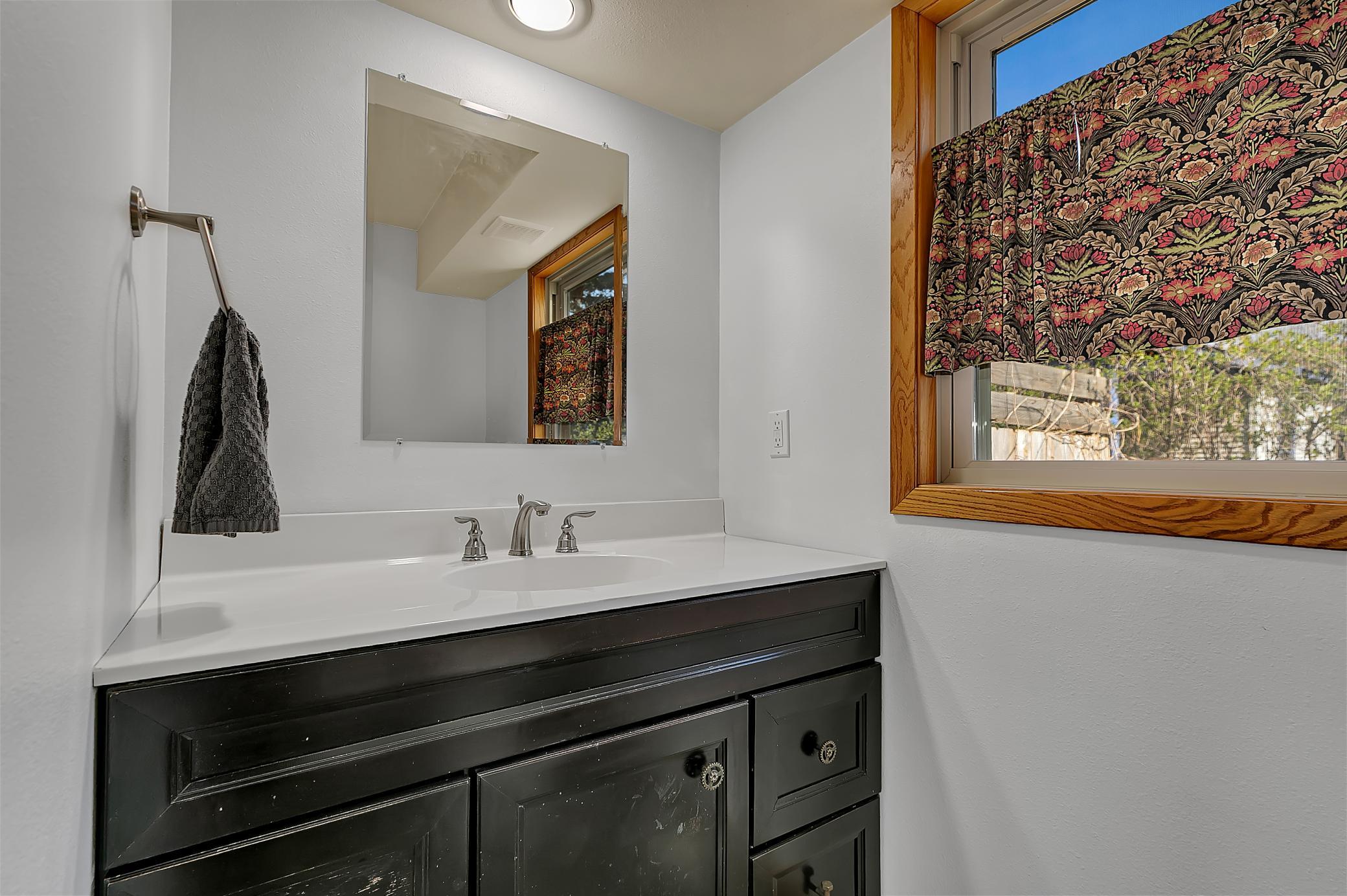 Half bath with large vanity, recessed lighting and tiled flooring.