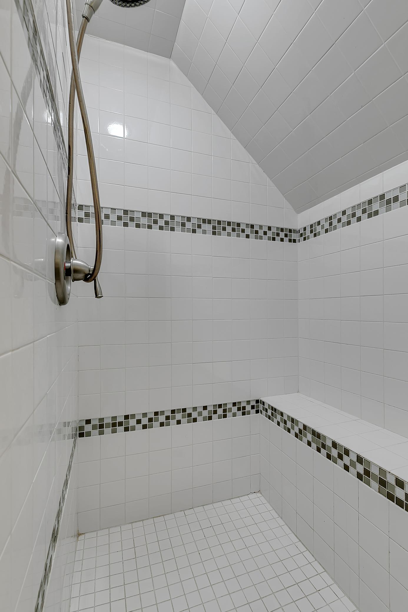 The shower is floor to ceiling tile with a built-in bench.