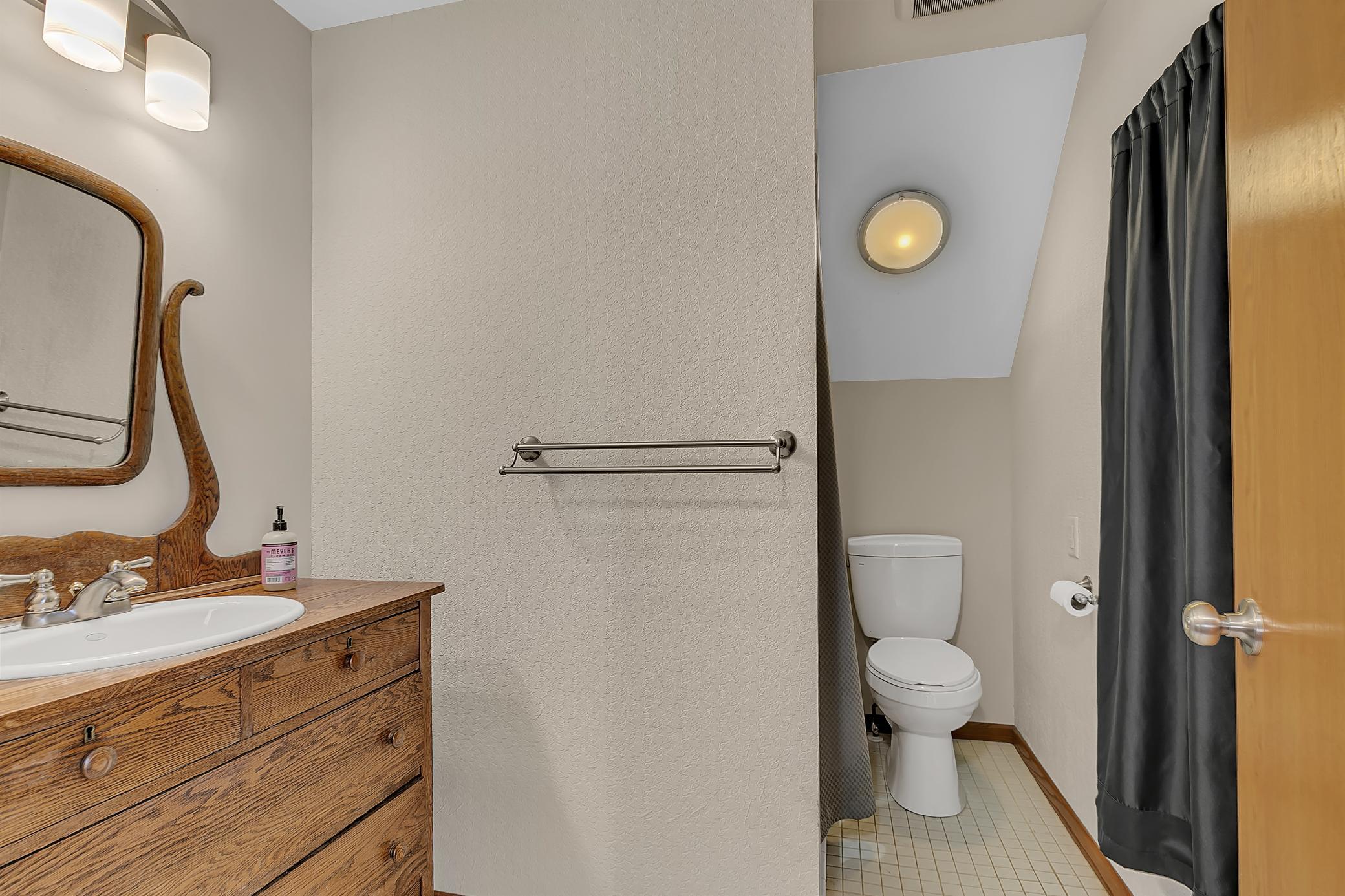 The bathroom also features updated lighting, towel bars, and tiled flooring.