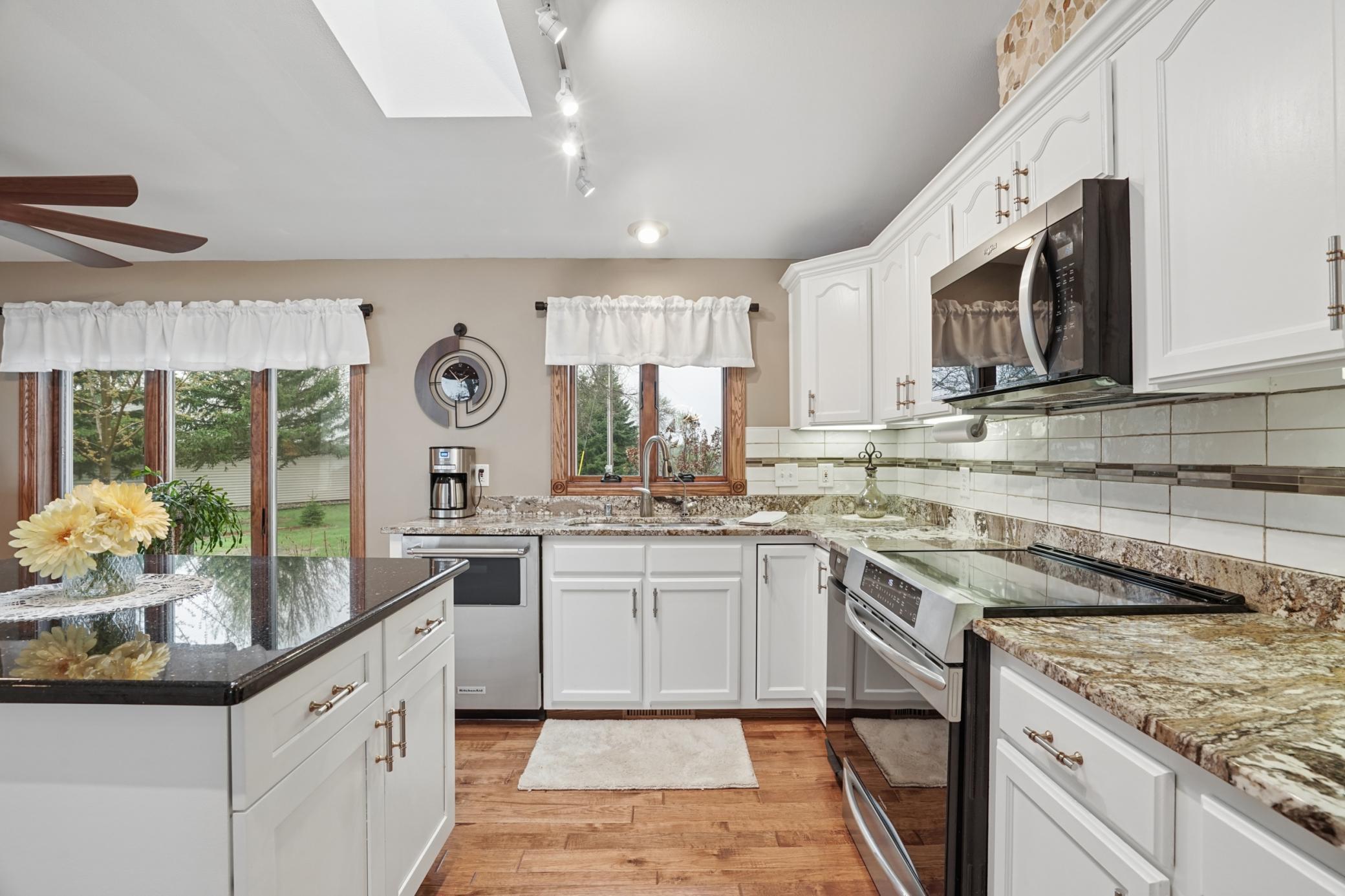The gourmet kitchen is a chef's dream, bathed in natural light from a skylight. Features include S.S. appliances, granite countertops, and a pantry.