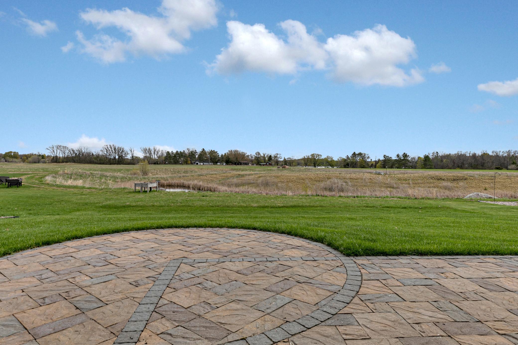 A large stone patio overlooks a backyard with no rear neighbors.
