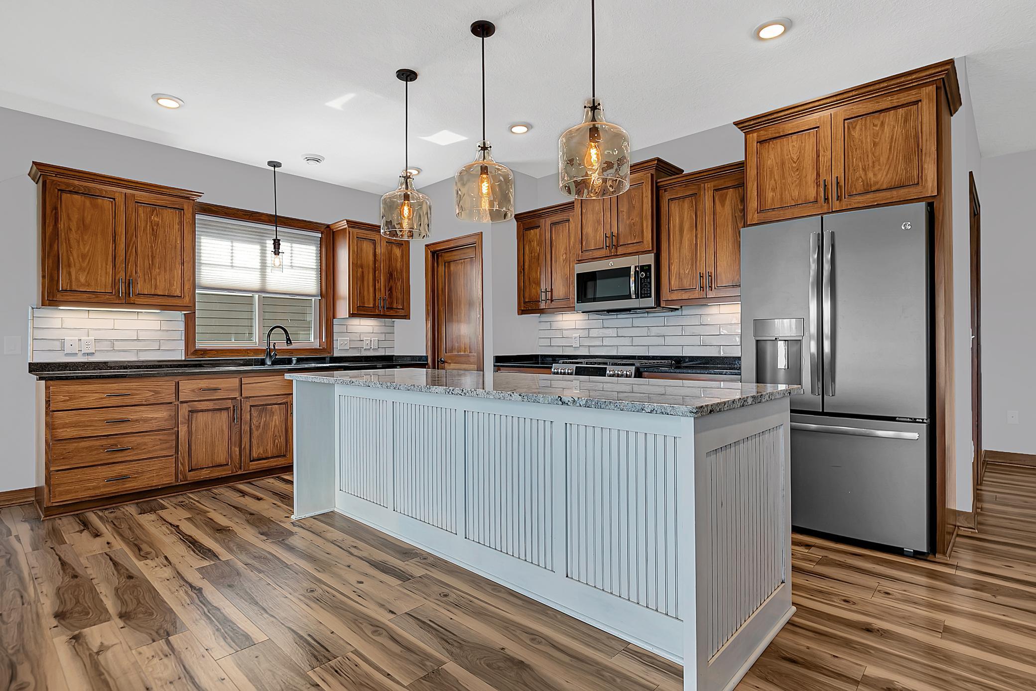 The kitchen is designed for both function and connection, boasting granite countertops, a tiled backsplash, and soft-close cabinetry.