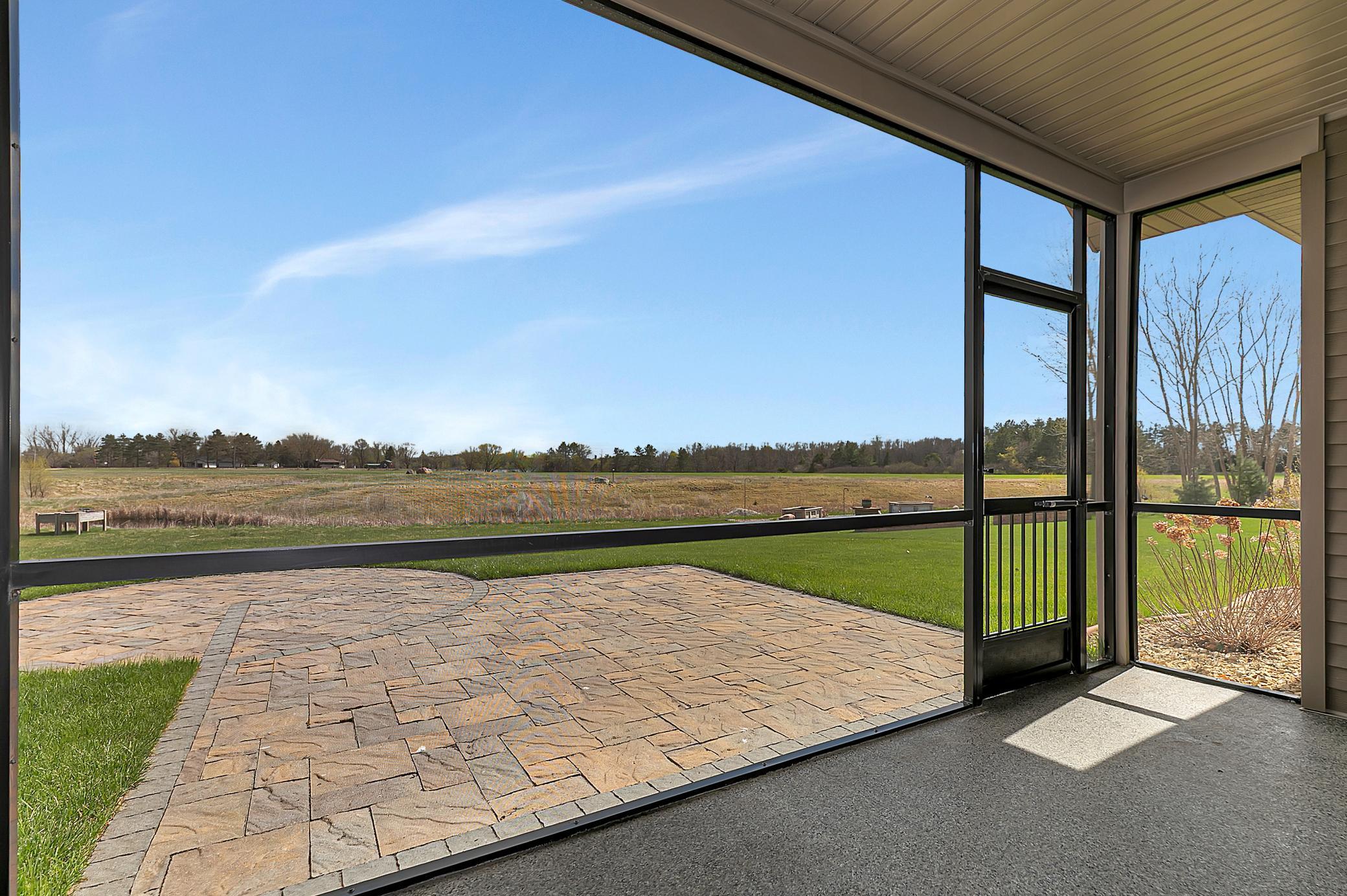 The screened-in porch leads out to a large stone patio overlooking a backyard with no neighbors.