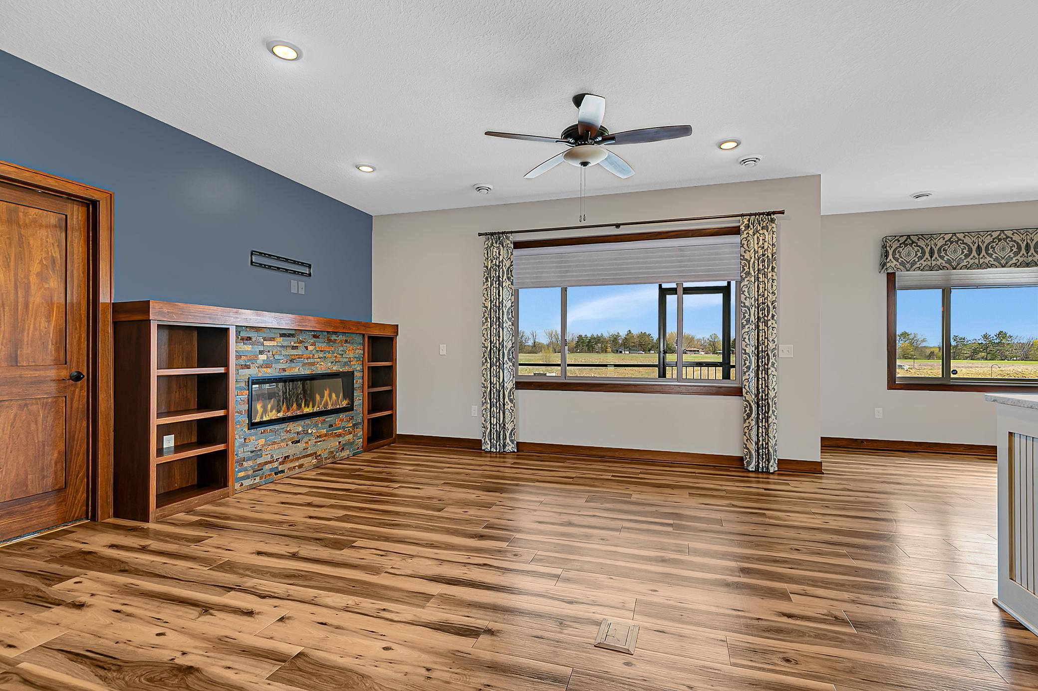 The open-concept living area is warm and inviting, highlighted by an electric fireplace with a beautiful surround and built-in bookshelves.