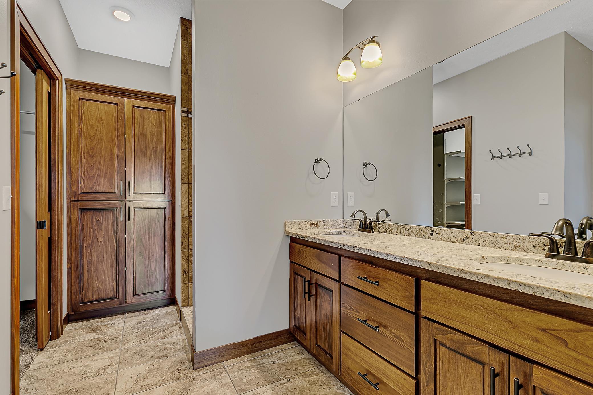 The primary en-suite offers private access through pocket doors to a spa-like bathroom with double sinks, granite vanity, and a built-in linen cabinet.