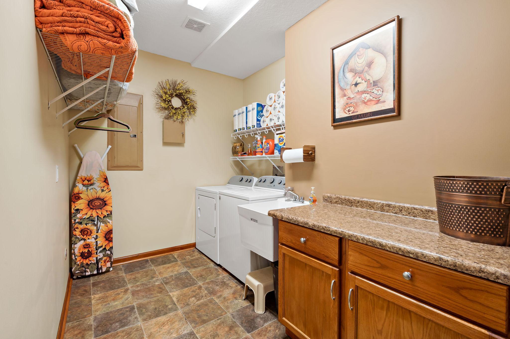 Clean, well organized laundry room with sink and storage.