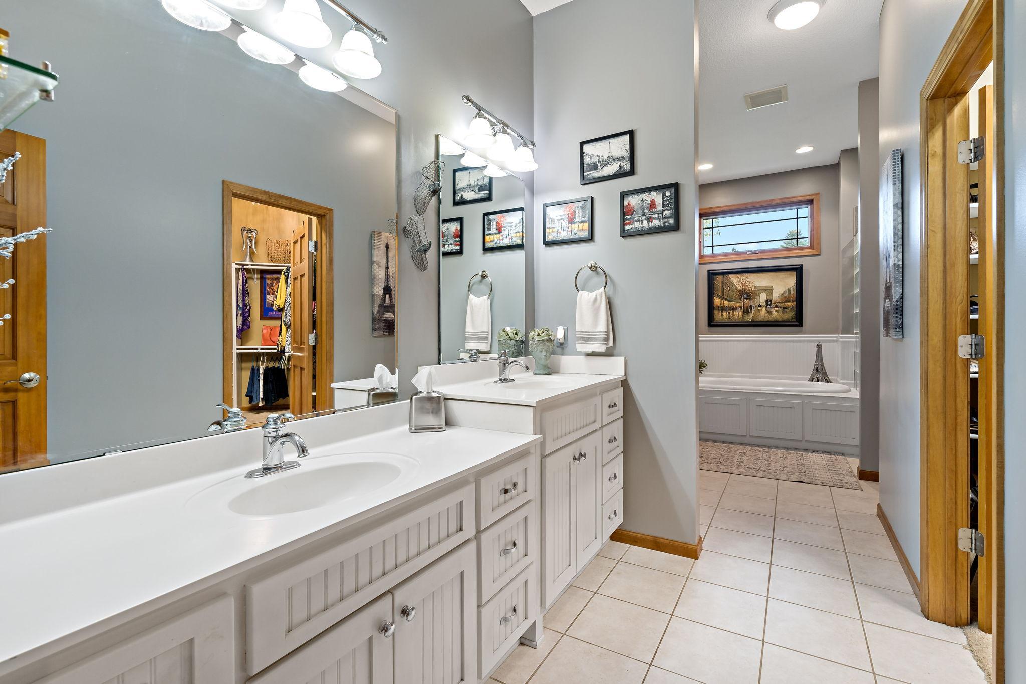 Massive primary bathroom with double vanity, soaking tub, shower, and walk-in closet.