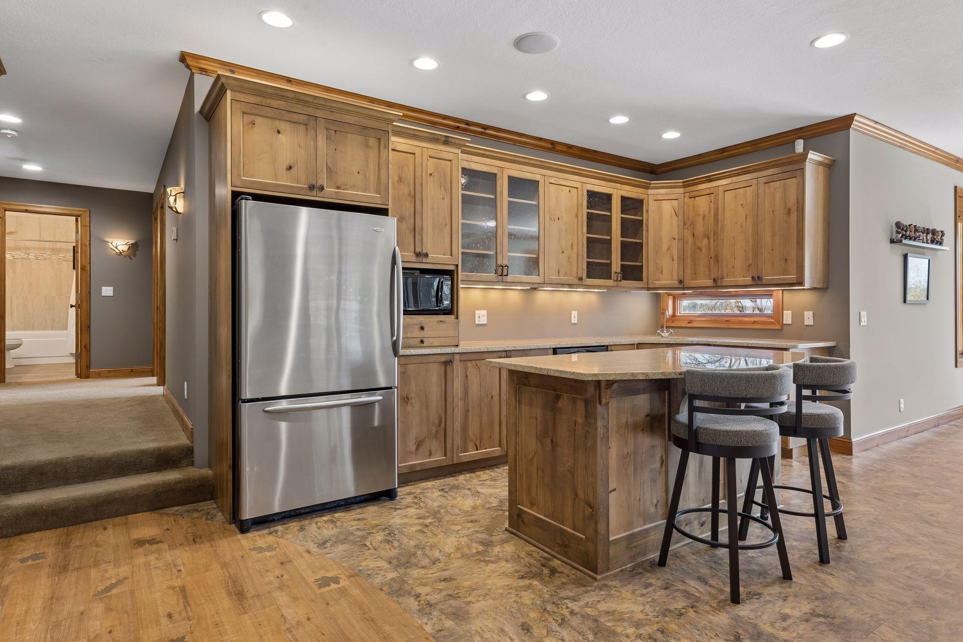 Lower-level kitchen/bar area with tons of cabinets, dishwasher, microwave, and refrigerator.