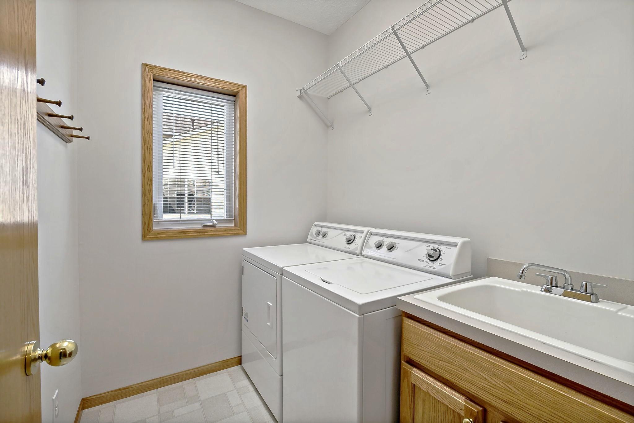 Convenient main floor laundry room w/ additional shelving and a window for natural light
