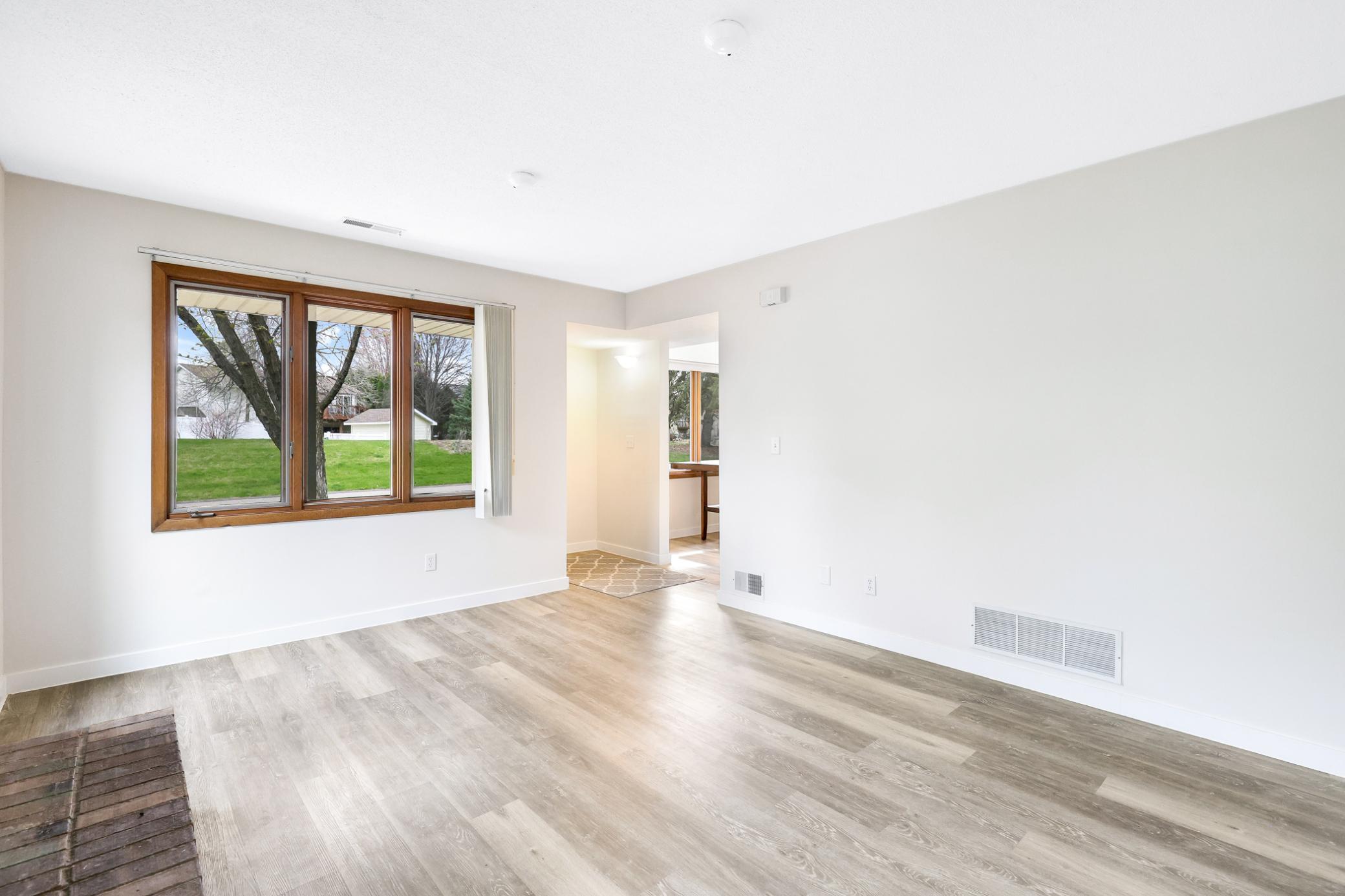 Spacious living room featuring durable flooring, abundant natural light, and a cozy fireplace—perfect for relaxing or entertaining.
