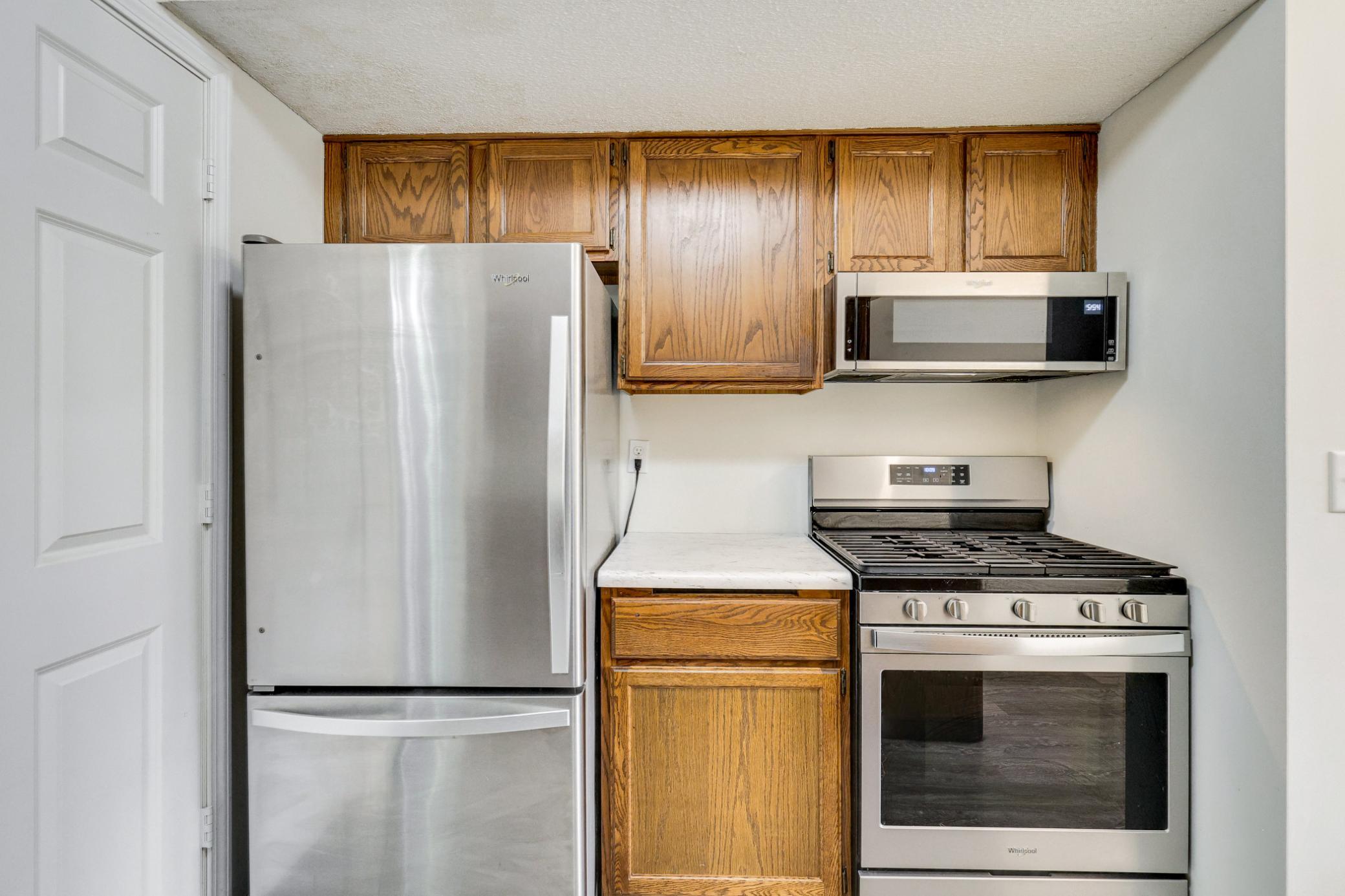 Updated stainless steel appliances including gas range and microwave, paired with ample cabinetry for storage.