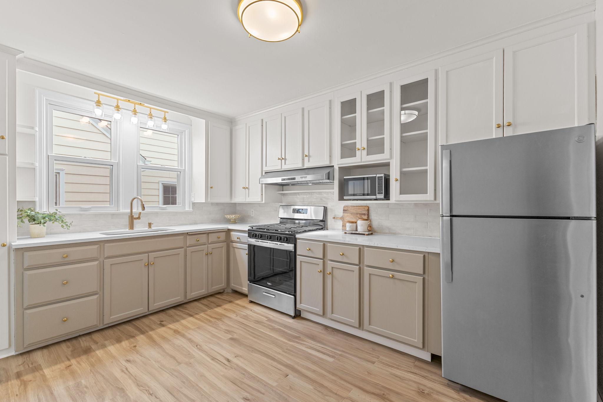 The kitchen in a showstopper with quartz countertops, new stainless steel appliances, and on-trend gold hardware.