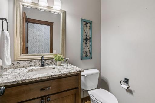 Main floor half bath with granite countertop and custom vanity. Tiled floors and matching hardware.