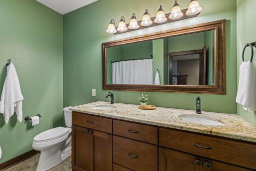 A spacious lower-level bathroom features a double vanity with granite countertops, ample storage, and the added comfort of heated tile floorsâproviding everyday luxury for guests and family alike.