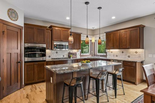 This beautifully appointed kitchen features rich custom cabinetry, granite countertops, a large center island with seating, birch hardwood floors, stainless steel appliances, and abundant prep space for everyday living and entertaining.