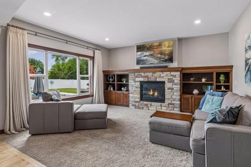 Relax in the warm and welcoming main-floor family room, highlighted by a stunning stone gas fireplace, custom built-in cabinetry, plush carpeting, and expansive windows overlooking the private backyard.