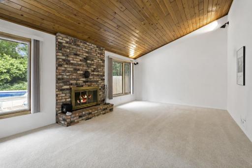 The main level living room to the back of the home with vaulted ceilings and views of the backyard pool. TV has been virtually removed.