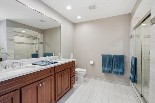 Updated Primary Bathroom: double vanity w/granite countertop, full tile wall shower w/glass door, tile floor, window and built-in makeup area w/granite top