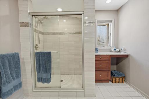 Updated Primary Bathroom: double vanity w/granite countertop, full tile wall shower w/glass door, tile floor, window and built-in makeup area w/granite top