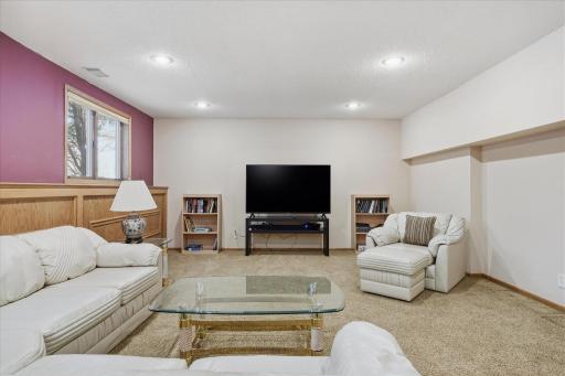 Awesome lower level Amusement Room with raised oak panel accent wall, recessed LED can lighting, updated neutral carpet and lookout windows for plenty of natural light
