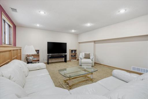 Awesome lower level Amusement Room with raised oak panel accent wall, recessed LED can lighting, updated neutral carpet and lookout windows for plenty of natural light