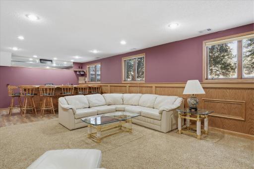Awesome lower level Amusement Room with raised oak panel accent wall, recessed LED can lighting, updated neutral carpet and lookout windows for plenty of natural light
