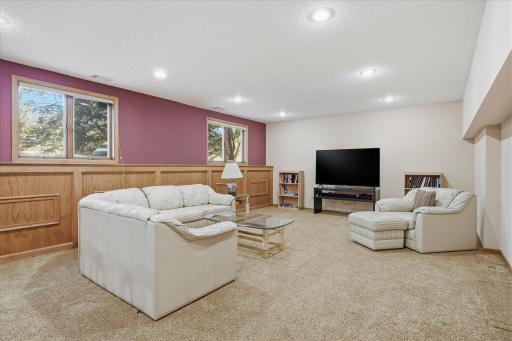 Awesome lower level Amusement Room with raised oak panel accent wall, recessed LED can lighting, updated neutral carpet and lookout windows for plenty of natural light