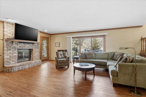 Walkout Family Room features: see-thru wood burning fireplace w/brick surround + wood mantel, hardwood floors, crown molding around ceiling, recessed accent lights and walkout sliding door to large maint-free deck for relaxing BBQs w/family