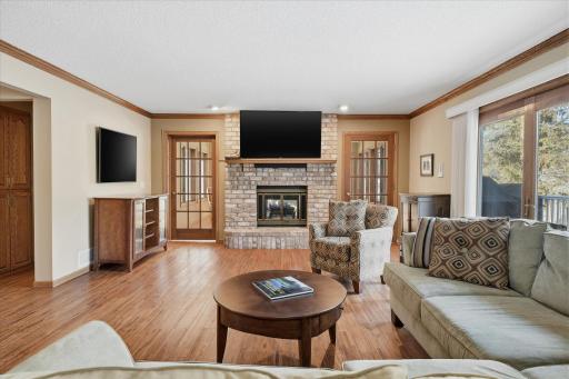 Open Family Room features: see-thru wood burning fireplace w/brick surround + wood mantel and hardwood floors