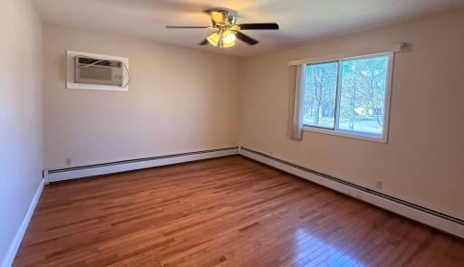 Primary bedroom with ceiling fan and personal a/c unit