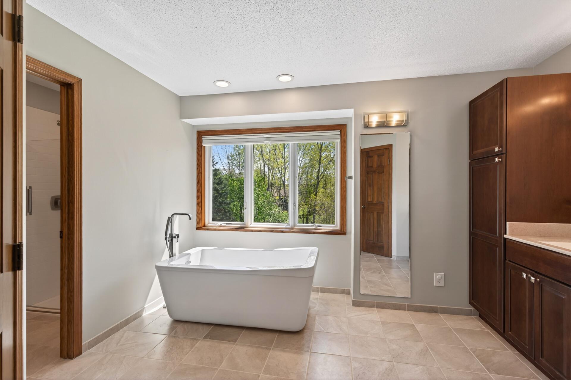 Primary bathroom soaking tub looks out to the backyard.