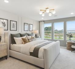 Welcome to the primary suite. All the modern designs flow seamlessly with ample space in both the bedroom and dual walk-in closets. Photo of model home.