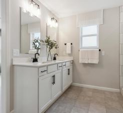 Private primary bathroom features a huge shower, linen closets and striking modern finishes! Photo of model home.