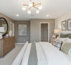 Welcome to the primary suite. All the modern designs flow seamlessly with ample space in both the bedroom and dual walk-in closets. Photo of model home.