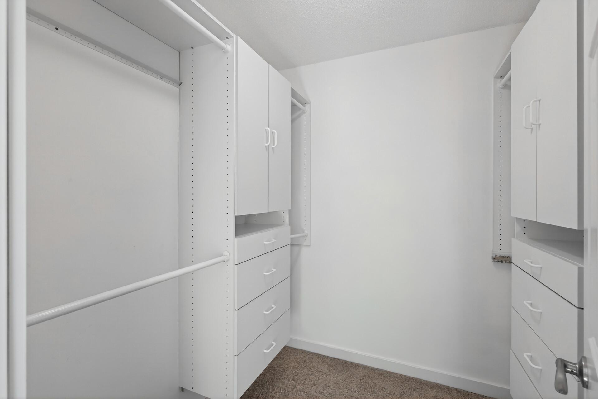 Primary walk-in closet with custom closet organizers.