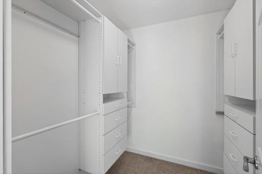 Primary walk-in closet with custom closet organizers.