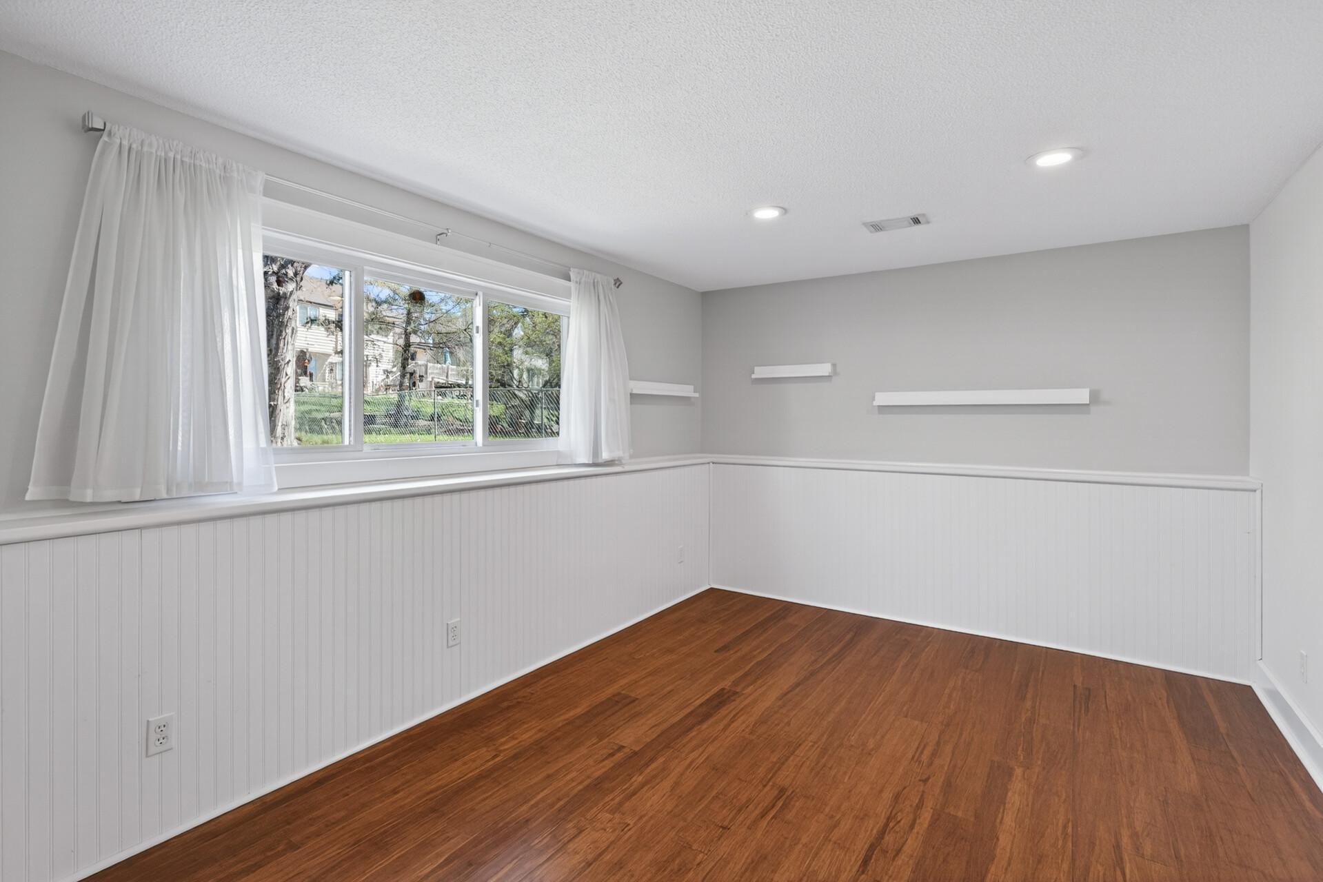 Generously-sized lower level bedroom with wainscotting and bamboo flooring.