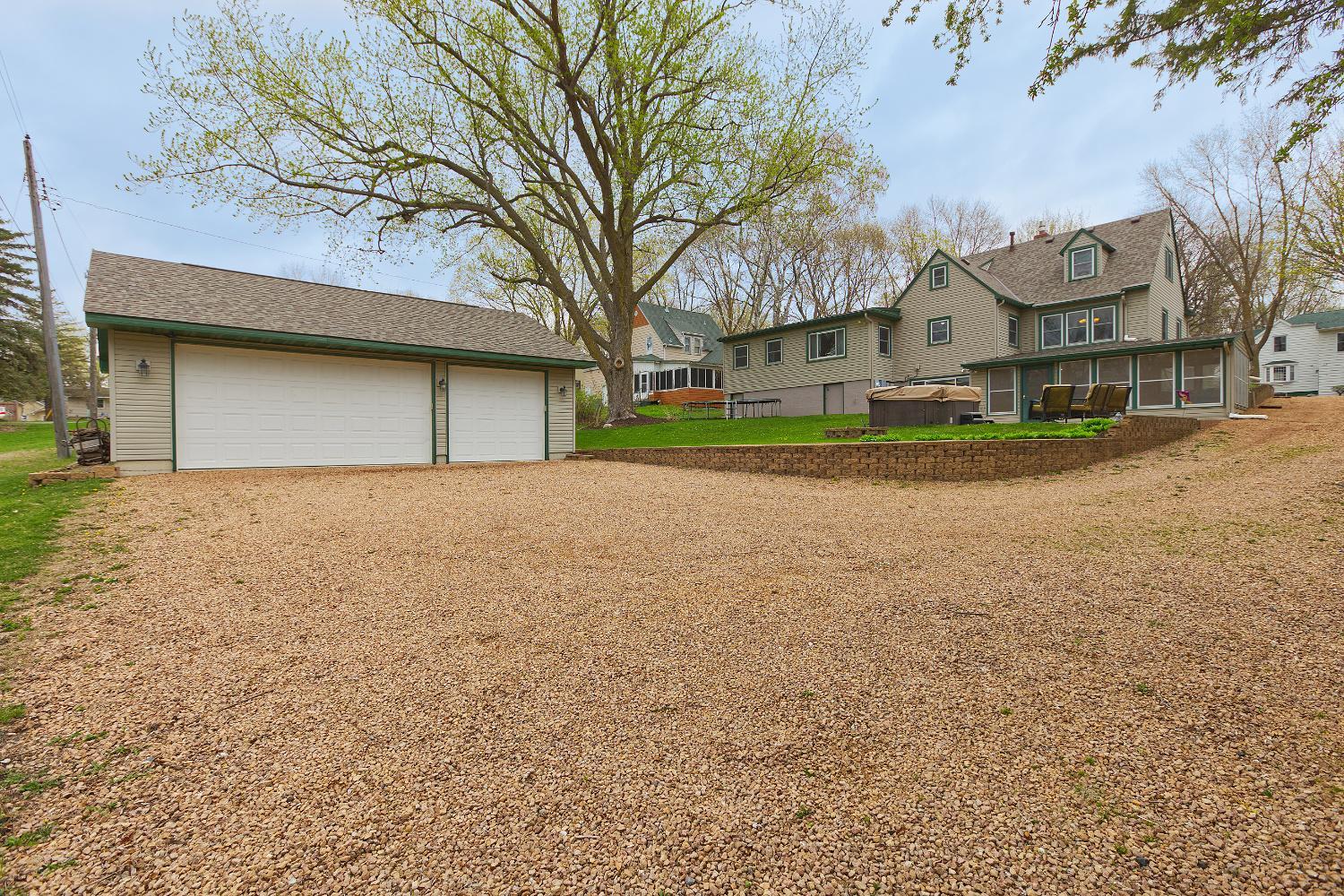 Back of home host the detached garage, patios and screen porch with lake views