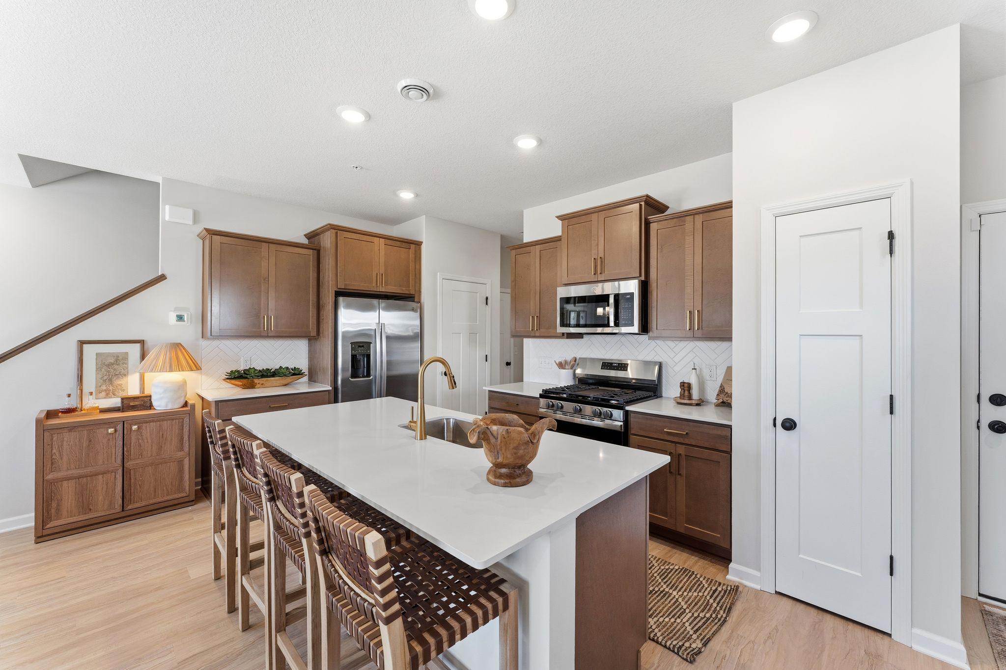 Kitchen features brown stained cabinets with gold hardware and white backsplash with all appliances included - for illustrative purposes only