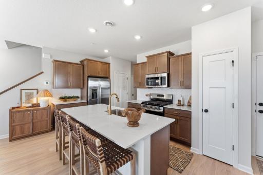 Kitchen features brown stained cabinets with gold hardware and white backsplash with all appliances included - for illustrative purposes only