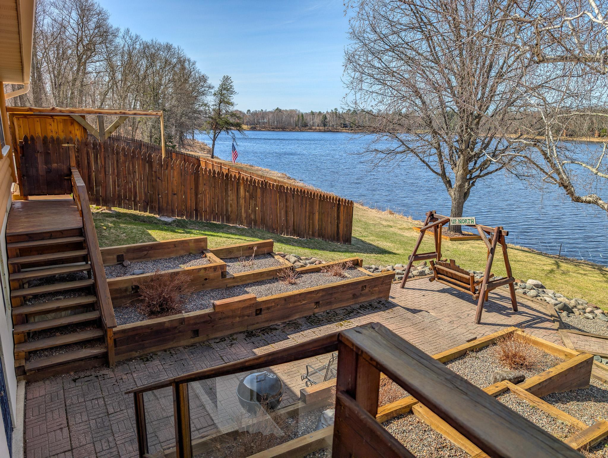 Landscaped lakeside deck and patio. The basement walkout to the patio. Pool in the background.