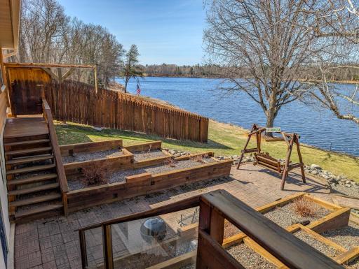 Landscaped lakeside deck and patio. The basement walkout to the patio. Pool in the background.