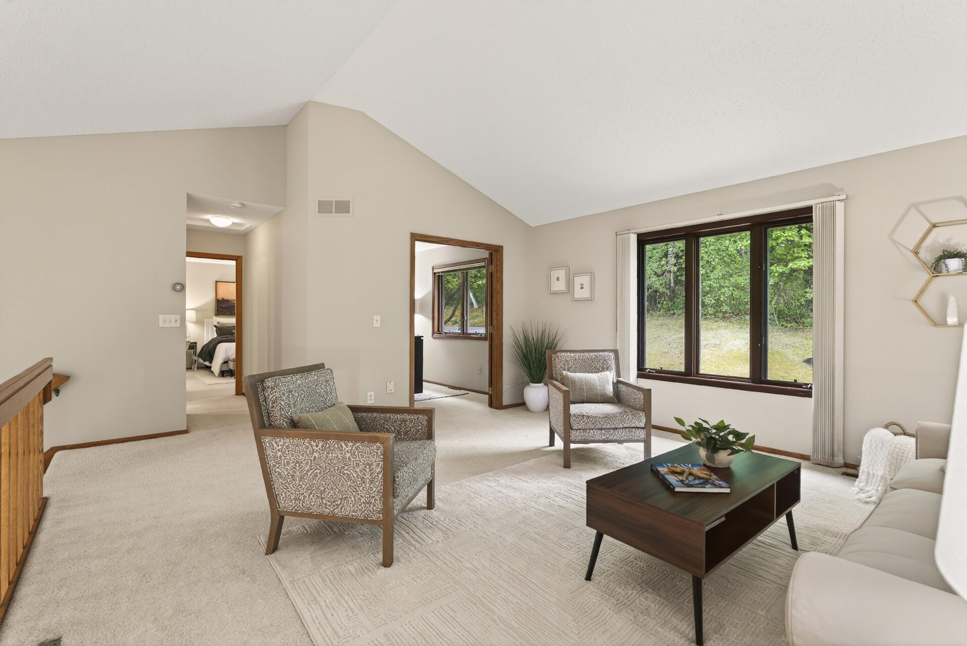 Living room is saturated in natural light and leads to the office:den