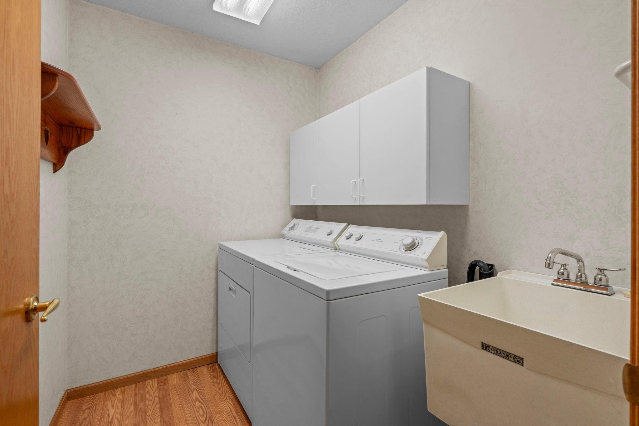 Laundry room features storage cabinets and a laundry sink.